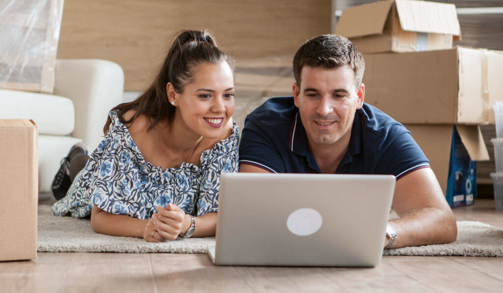 couple on the floor using a laptop surrounded by boxes